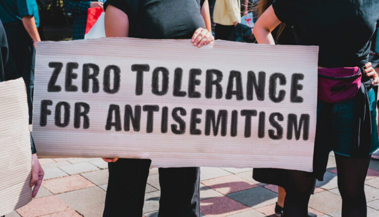A person holds a sign reading 'Zero tolerance for antisemitism'