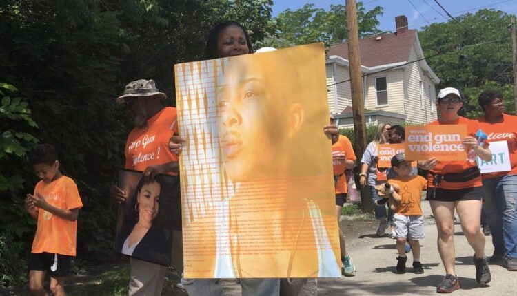 In this June photo, Ramona Reeves of Uniontown walks down Evans Street while holding an image of her son, Semori K. Wilson, who was killed in 2018. Reeves founded the SKW Foundation, which co-sponsors the Wear Orange Day (Herald-Standard photo).