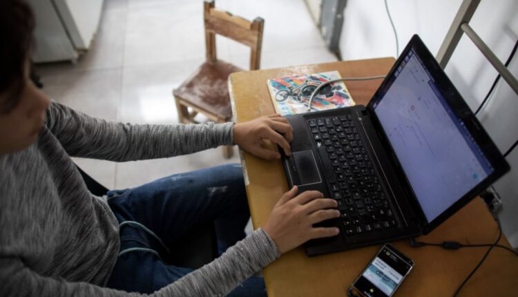 A teenager uses a laptop with a phone nearby. States are passing laws designed to keep kids away from social media and porn sites, but the effectiveness of the laws is being questioned by opponents and challenged in court (Leonardo Fernandez Viloria/Getty Images).